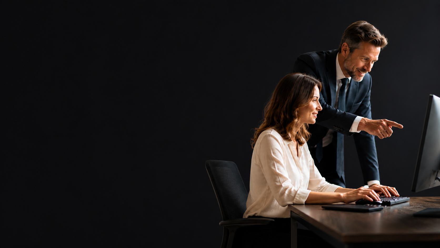 A specialist pointing out features on a computer screen while helping a colleague